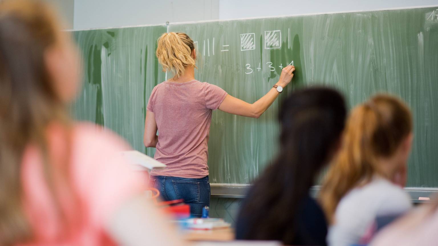 Eine Lehrerin schreibt im Mathematikunterricht einer achten Klasse an eine Schultafel. Gewalt gegen Lehrkräfte ist in Deutschland ein wachsendes Problem.