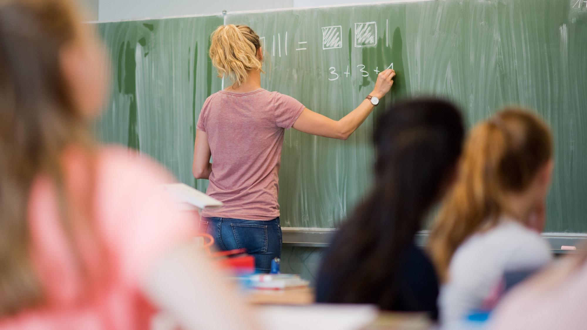 ARCHIV - 17.08.2016, Niedersachsen, Hannover: Eine Lehrerin schreibt im Mathematikunterricht einer achten Klasse an eine Schultafel. Gewalt gegen Lehrkräfte und Schulleitungen ist in Deutschland einer Umfrage zufolge «an der Tagesordnung» und ein wachsendes Problem. (zu dpa: «Umfrage unter Schulleitungen: Lehrkräfte als Zielscheibe von Gewalt») Foto: Julian Stratenschulte/dpa +++ dpa-Bildfunk +++