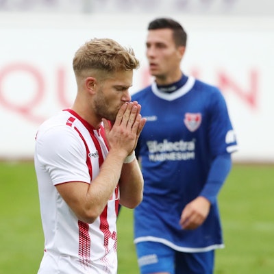 Ein Fußballspieler ist nach einer vergebenen Chance enttäuscht und hält sich die Hände vor den Mund.