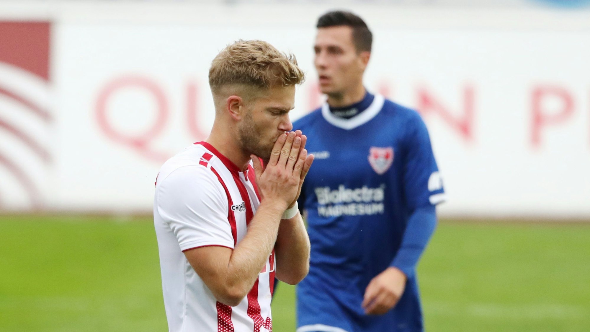 Ein Fußballspieler ist nach einer vergebenen Chance enttäuscht und hält sich die Hände vor den Mund.