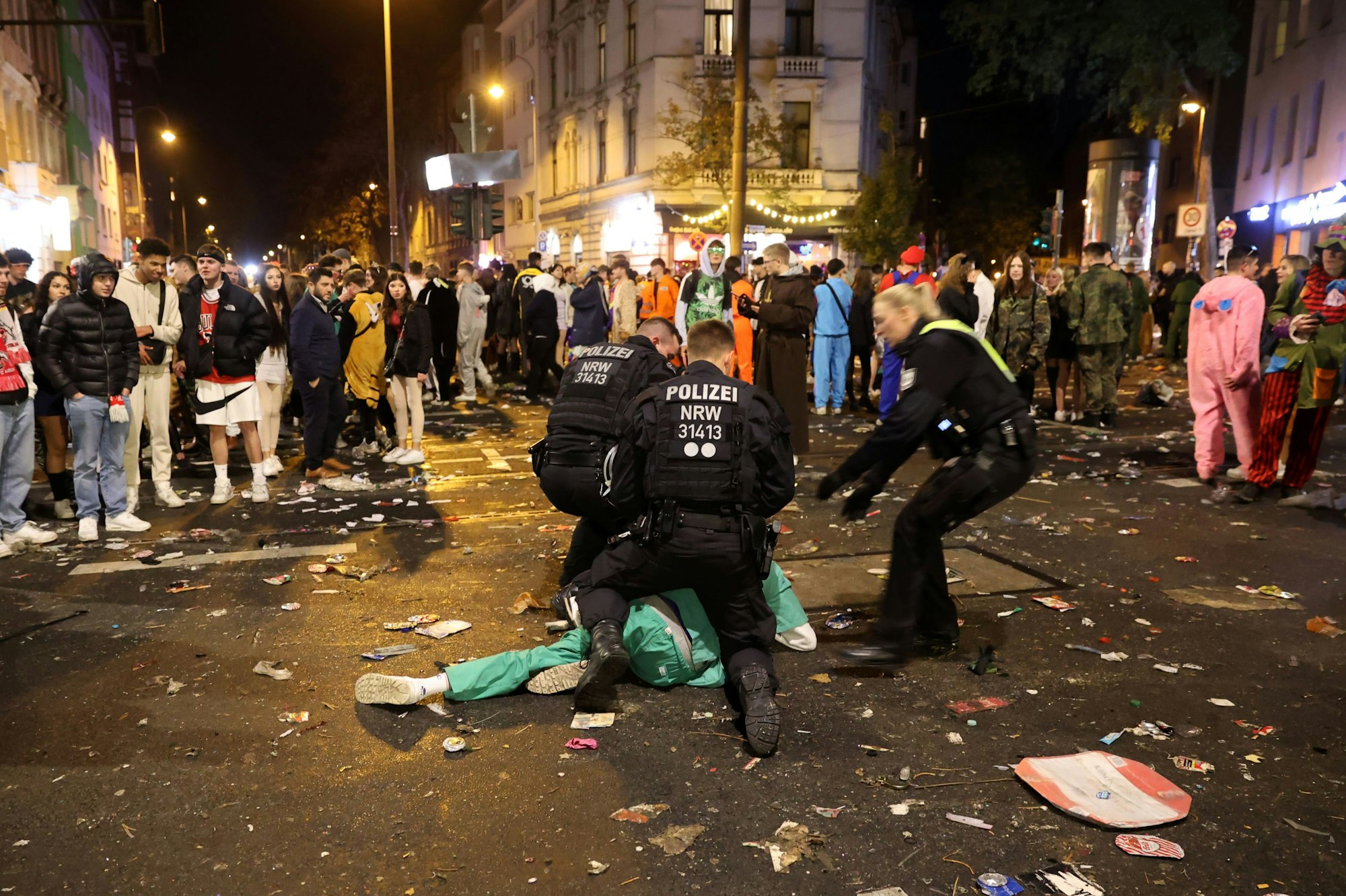 Sessionsauftakt Kölner Karneval: Festnahme einer am Boden liegenden Person in einer Menge von Feiernden auf der Zülpicher Straße durch die Polizei.