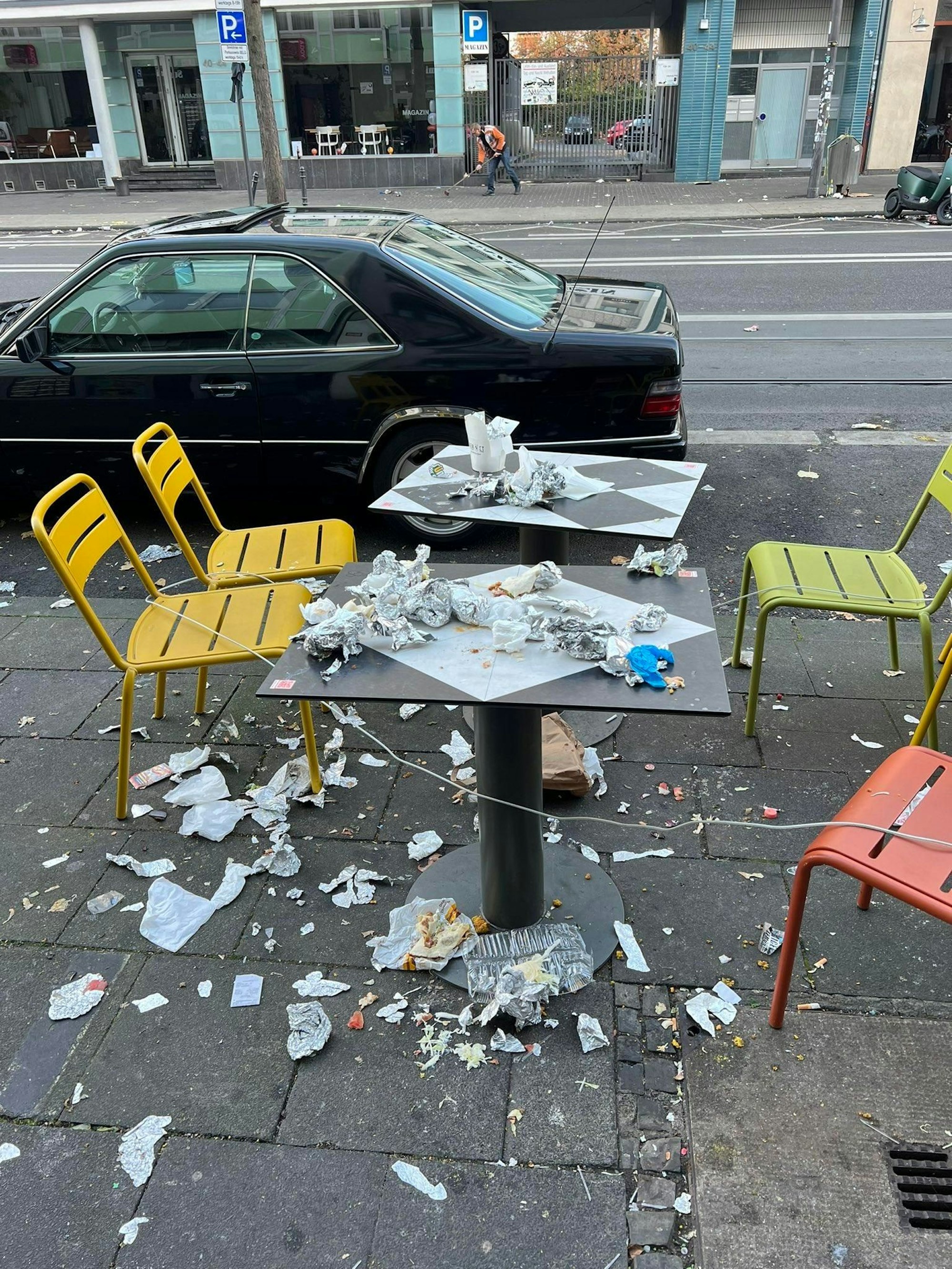 Ein Tisch mit vier Stühlen vor einer Gaststätte an der Aachener Straße ist mit Müll übersät.