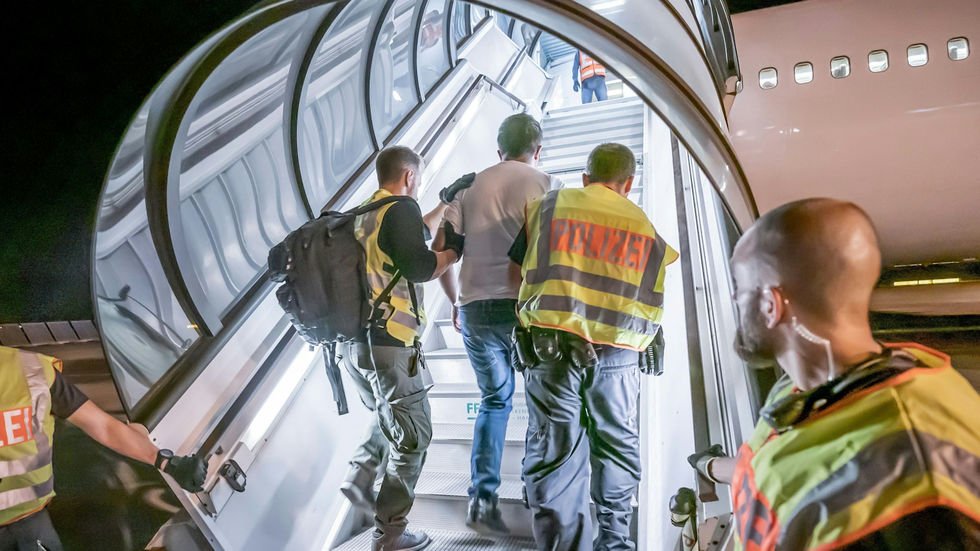 Sachsen, Leipzig: Polizeibeamte begleiten einen Afghanen auf dem Flughafen Leipzig-Halle in ein Charterflugzeug. Deutschland schiebt vorerst keine Menschen mehr nach Afghanistan ab.