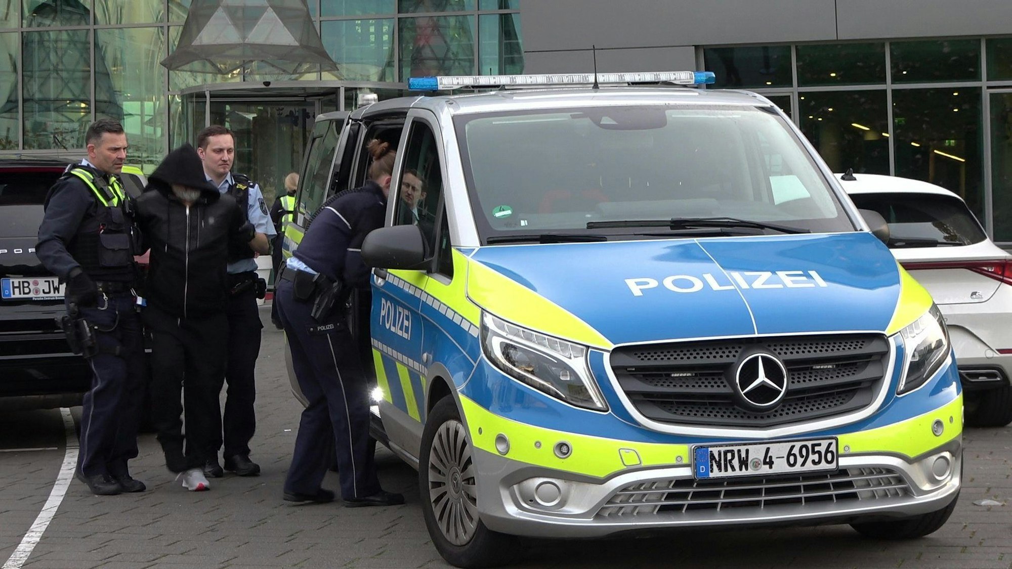 Polizeibeamte sind nach einer unklaren Bedrohungslage an einem Bonner Hotel im Einsatz und führen einen Mann ab und zu einem Polizeiauto.