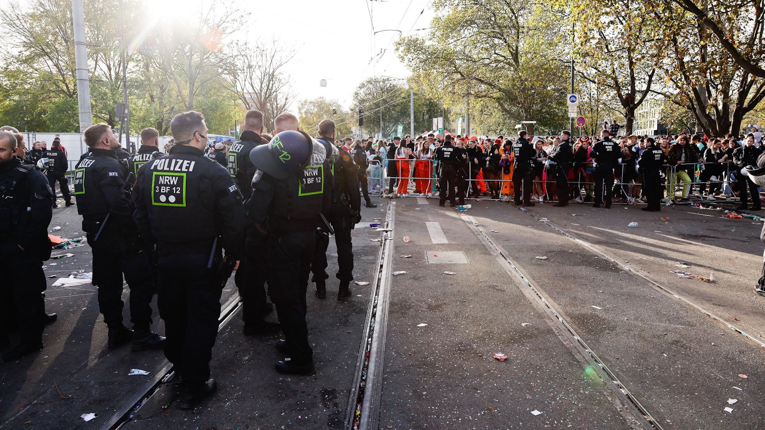 Polizisten und Feiernde stehen am 11.11. auf den gesperrten Gleisen der KVB an der Unimensa in Köln.