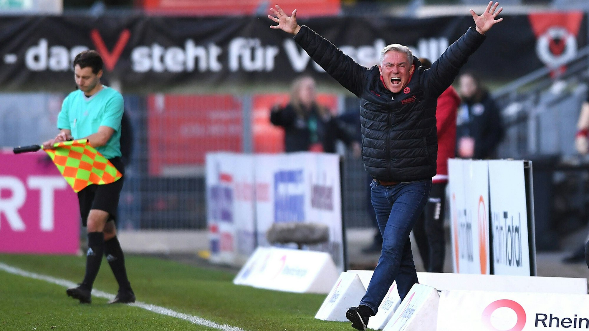 Ein Fußballtrainer bejubelt am Spielfeldrand den Sieg seines Teams.