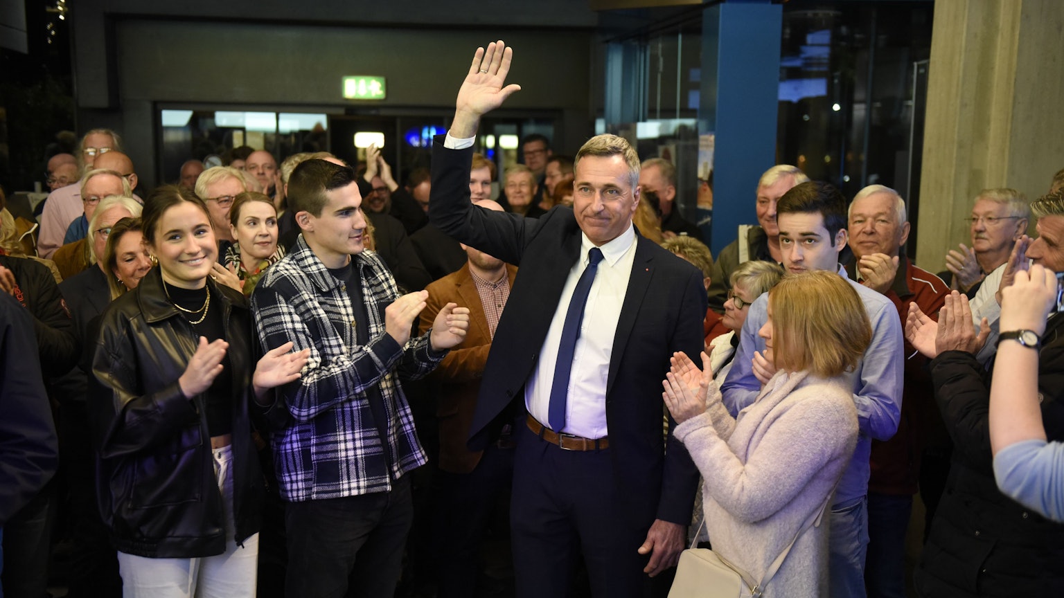 Ralph Manzke, neuer Bürgermeister in Wesseling, steht vor zahlreichen Menschen und feiert seinen Wahlsieg. Er trägt einen Anzug mit blauer Krawatte.