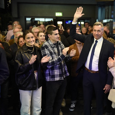 Ralph Manzke, neuer Bürgermeister in Wesseling, steht vor zahlreichen Menschen und feiert seinen Wahlsieg. Er trägt einen Anzug mit blauer Krawatte.
