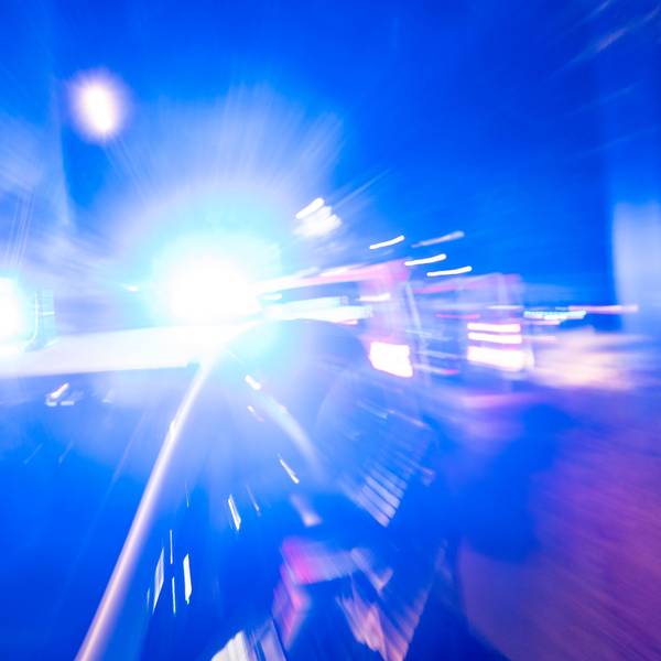 Ein Polizeiauto steht vor einem Haus, das Blaulicht strahl grell.