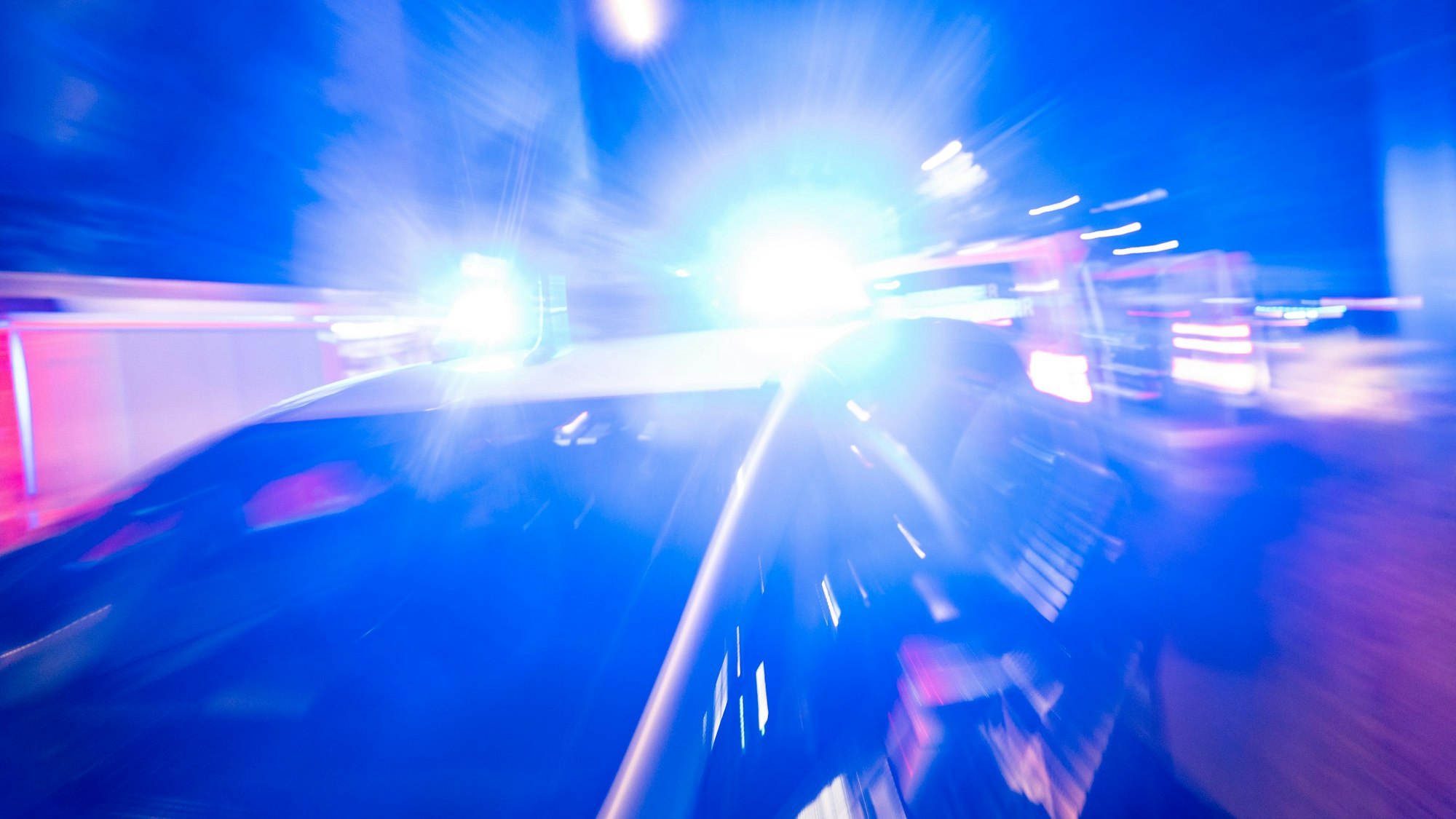 Ein Polizeiauto steht vor einem Haus, das Blaulicht strahl grell.