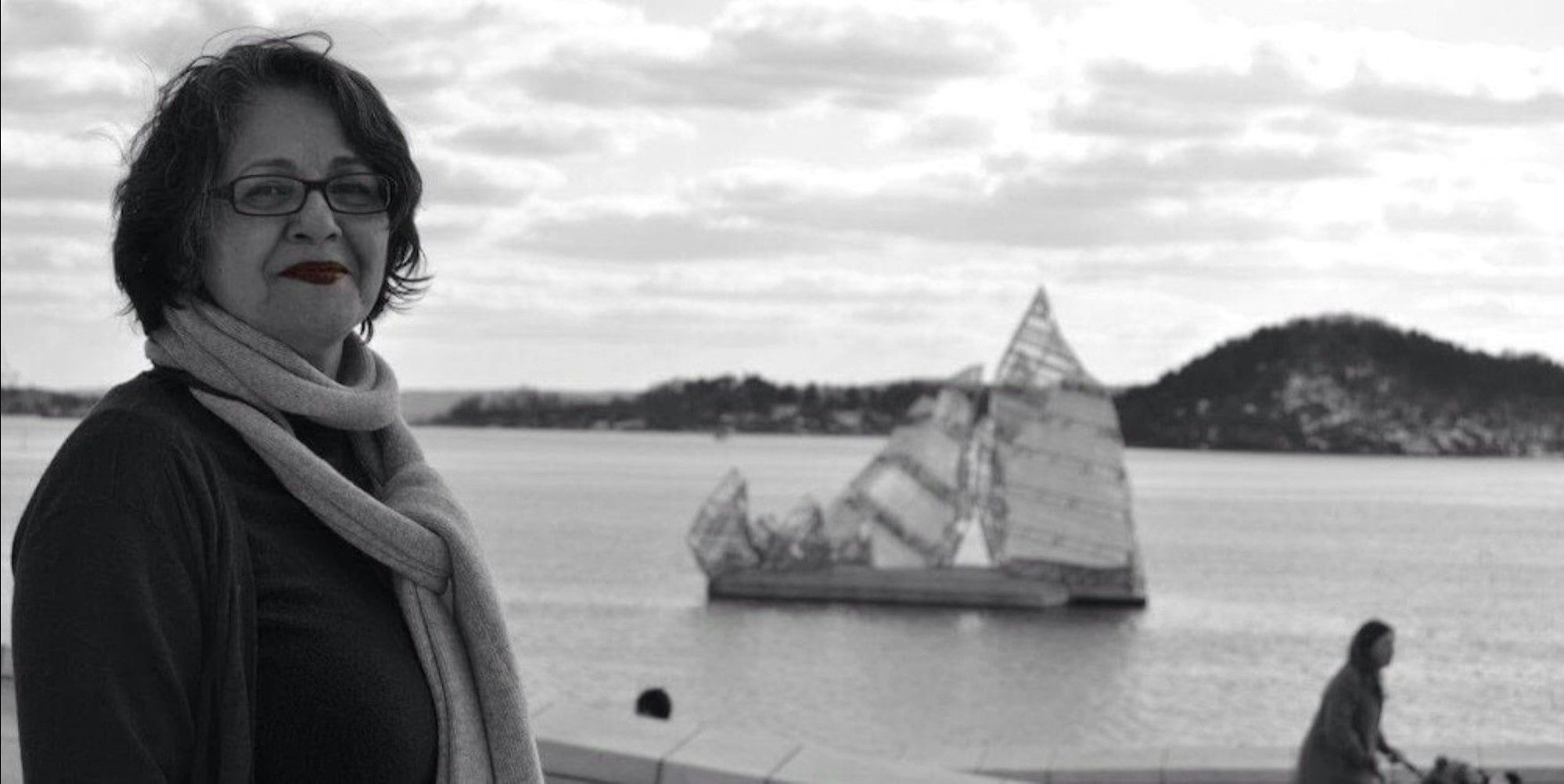 Die Kölnerin und Deutsch-Iranerin Nahid Taghavi ist auf einem Schwarz-Weiß-Foto vor Wasser zu sehen, im Hintergrund sind Berge.