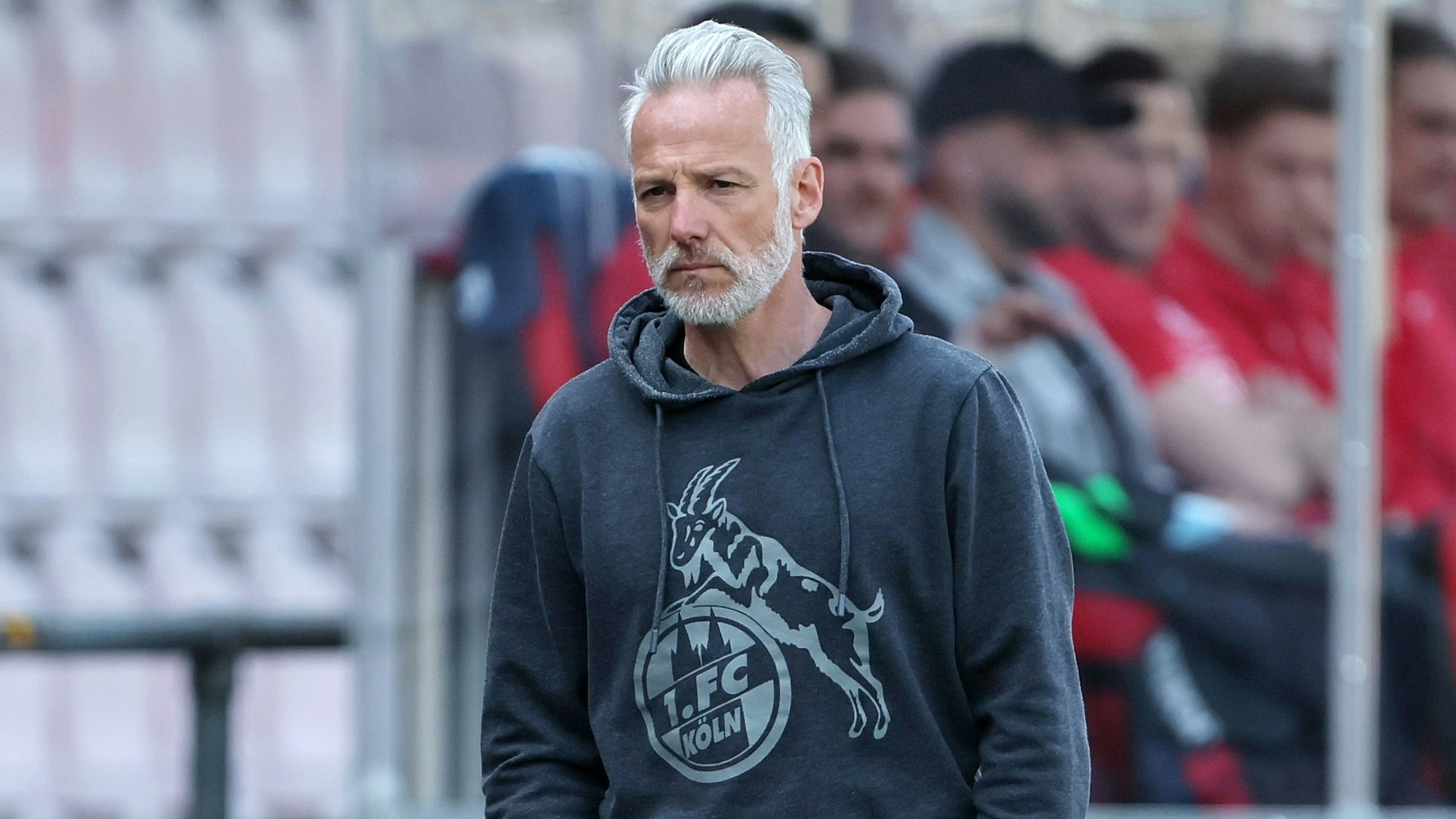 Ein Fußballtrainer steht mit ernster Miene am Spielfeldrand.