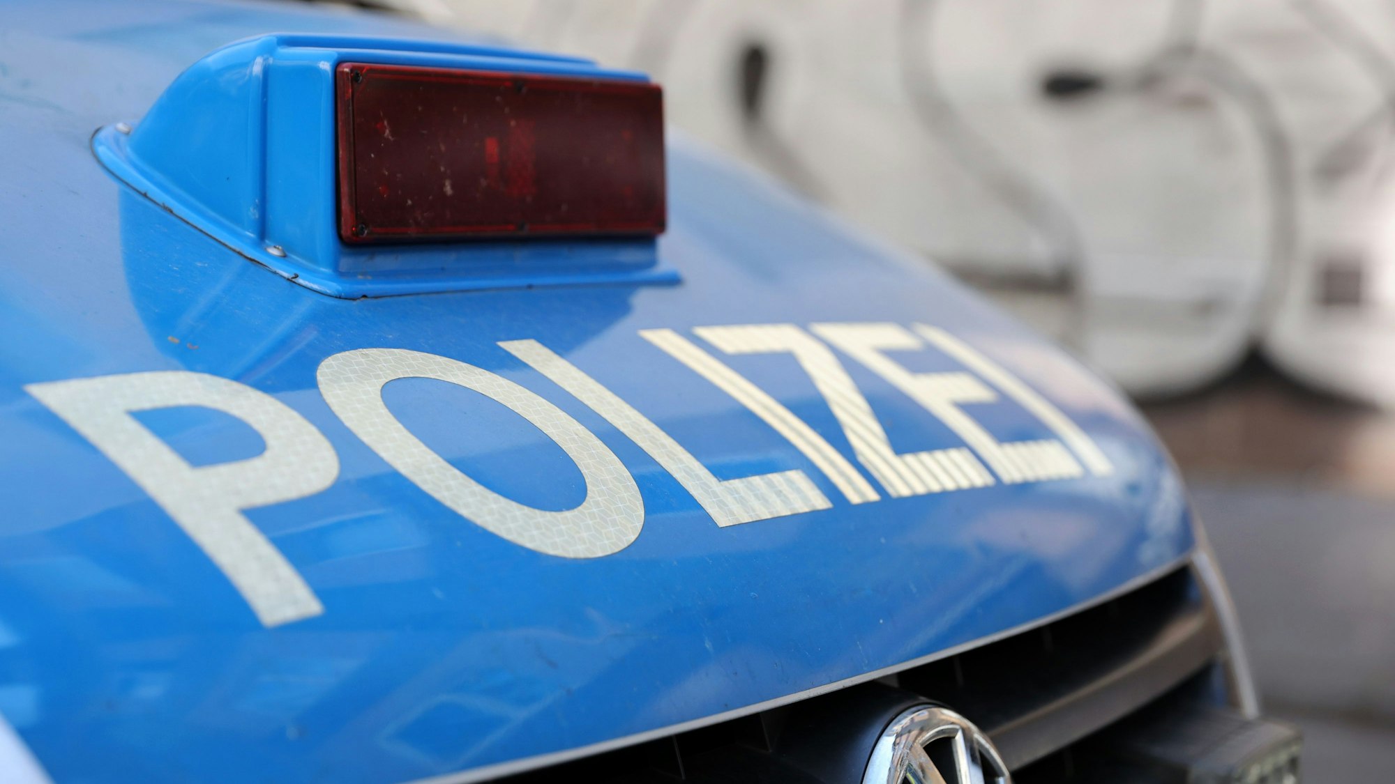Ein Polizeiauto mit der Aufschrift „Polizei“ in weiß auf der blauen Motorhaube.