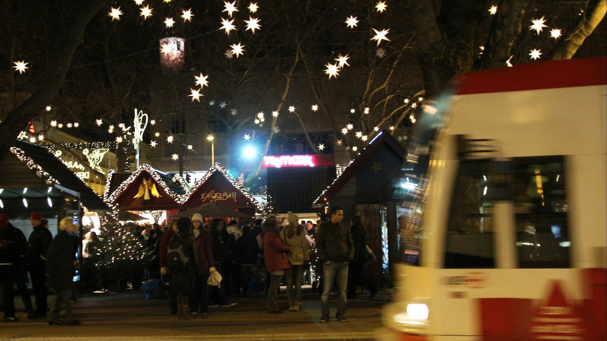 Eine Bahn der KVB hält vor dem weihnachtlich ausgeleuchteten Neumarkt.
