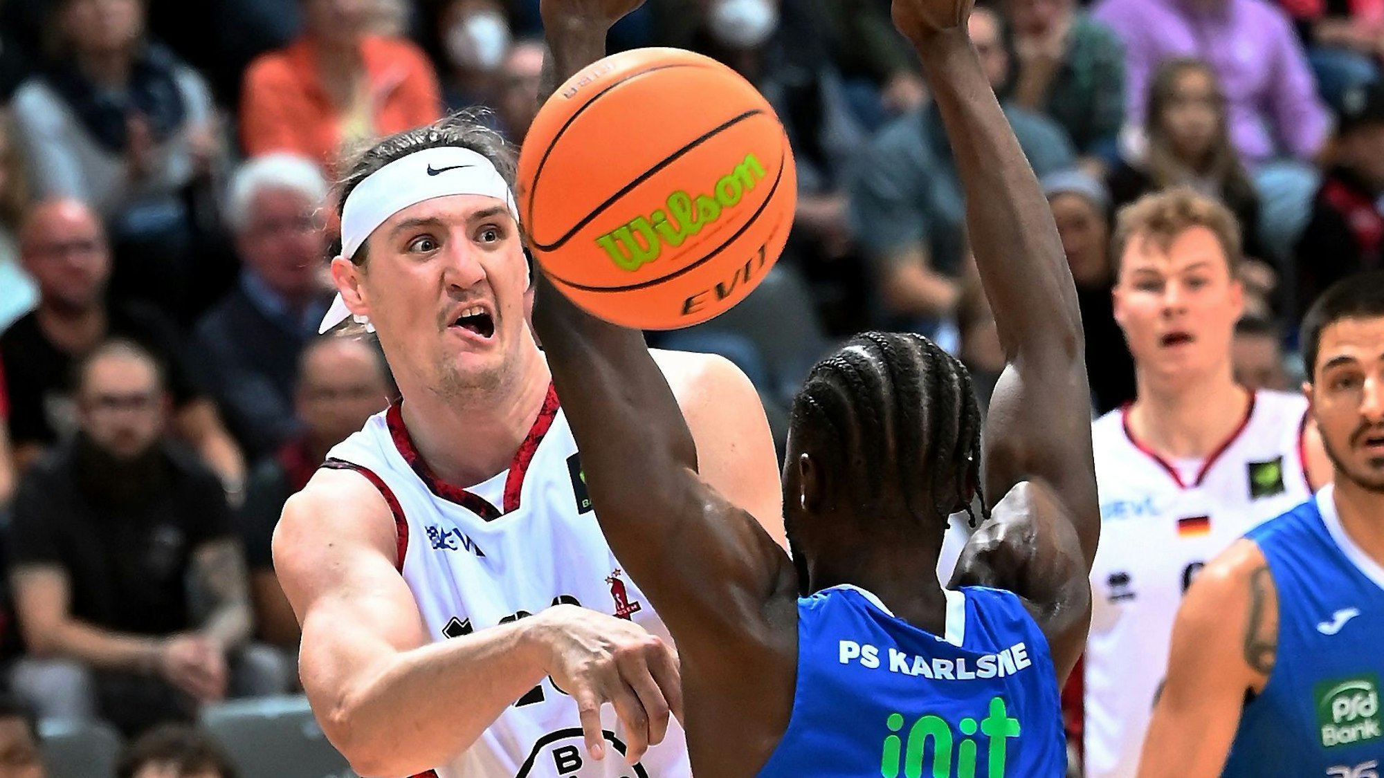 Ein Basketballspieler passt den Ball am Arm seines Gegners vorbei.