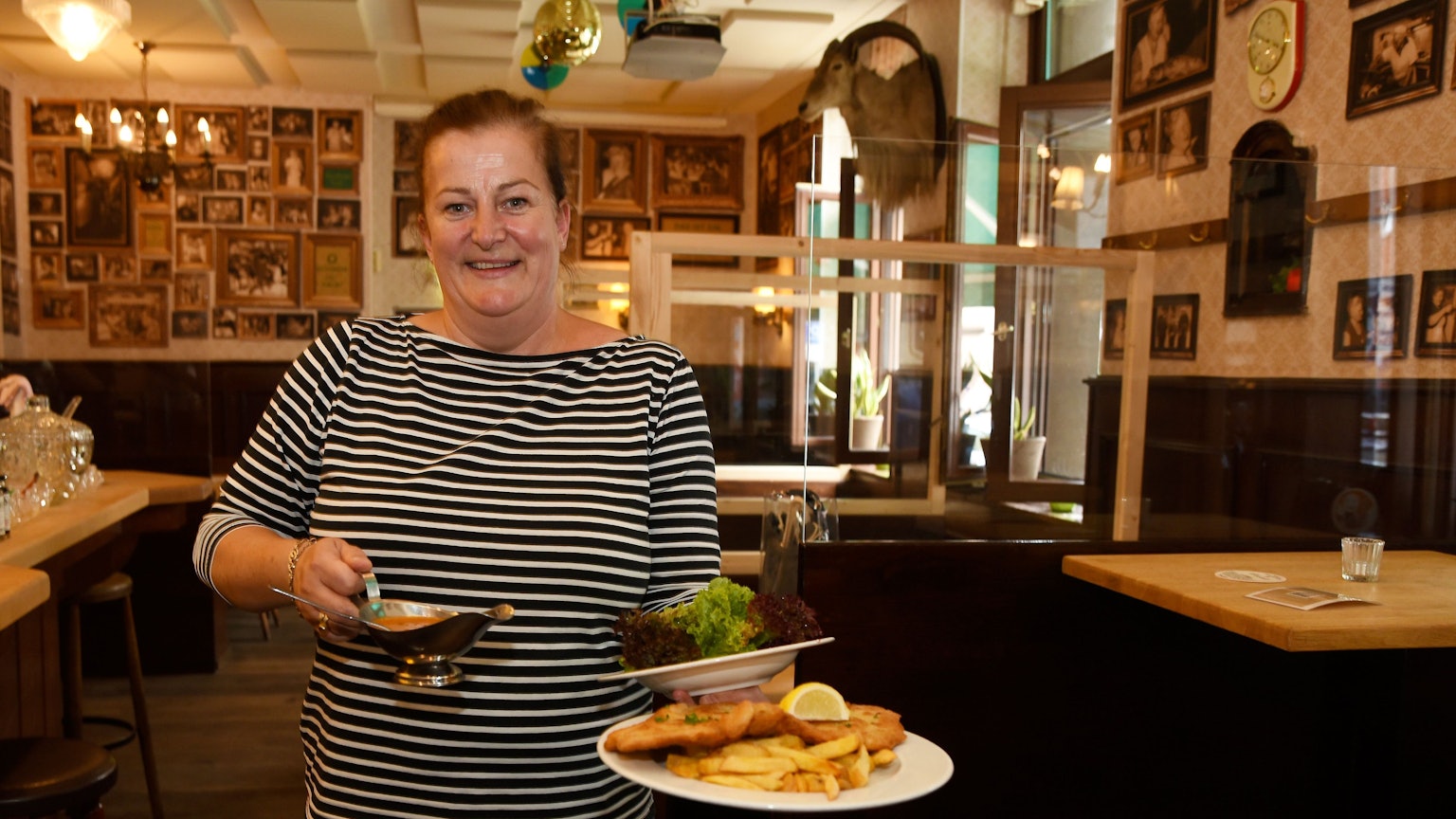 Wirtin Maureen Wolf steht in der Gaststätte Oma Kleinmann auf der Zülpicher Straße. In der Hand trägt sie einen Schnitzelteller.
