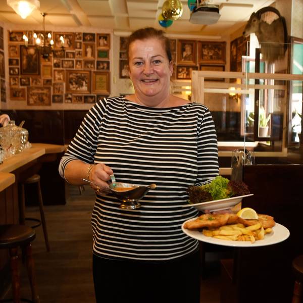 Wirtin Maureen Wolf steht in der Gaststätte Oma Kleinmann auf der Zülpicher Straße. In der Hand trägt sie einen Schnitzelteller.