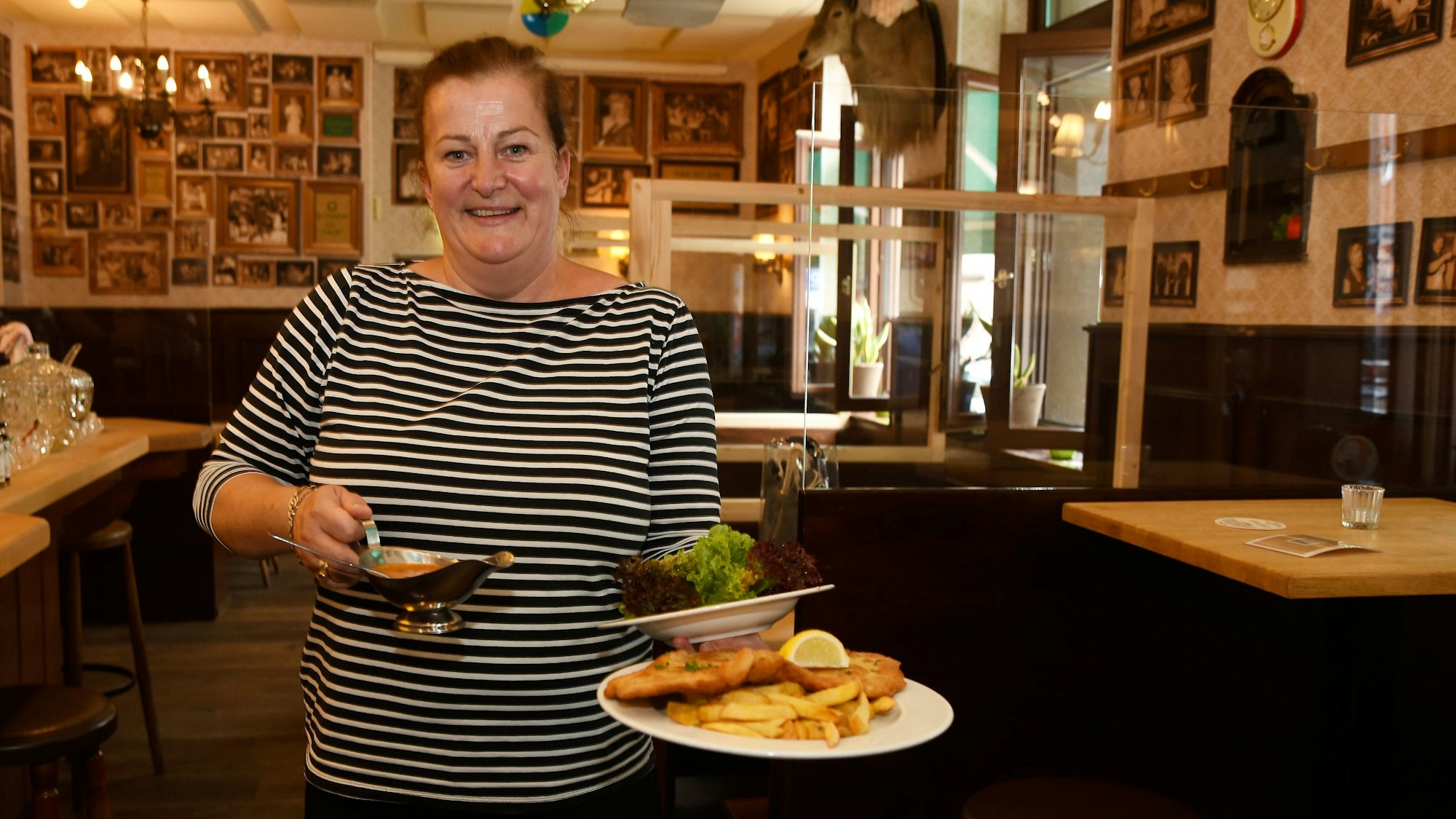 Wirtin Maureen Wolf steht in der Gaststätte Oma Kleinmann auf der Zülpicher Straße. In der Hand trägt sie einen Schnitzelteller.