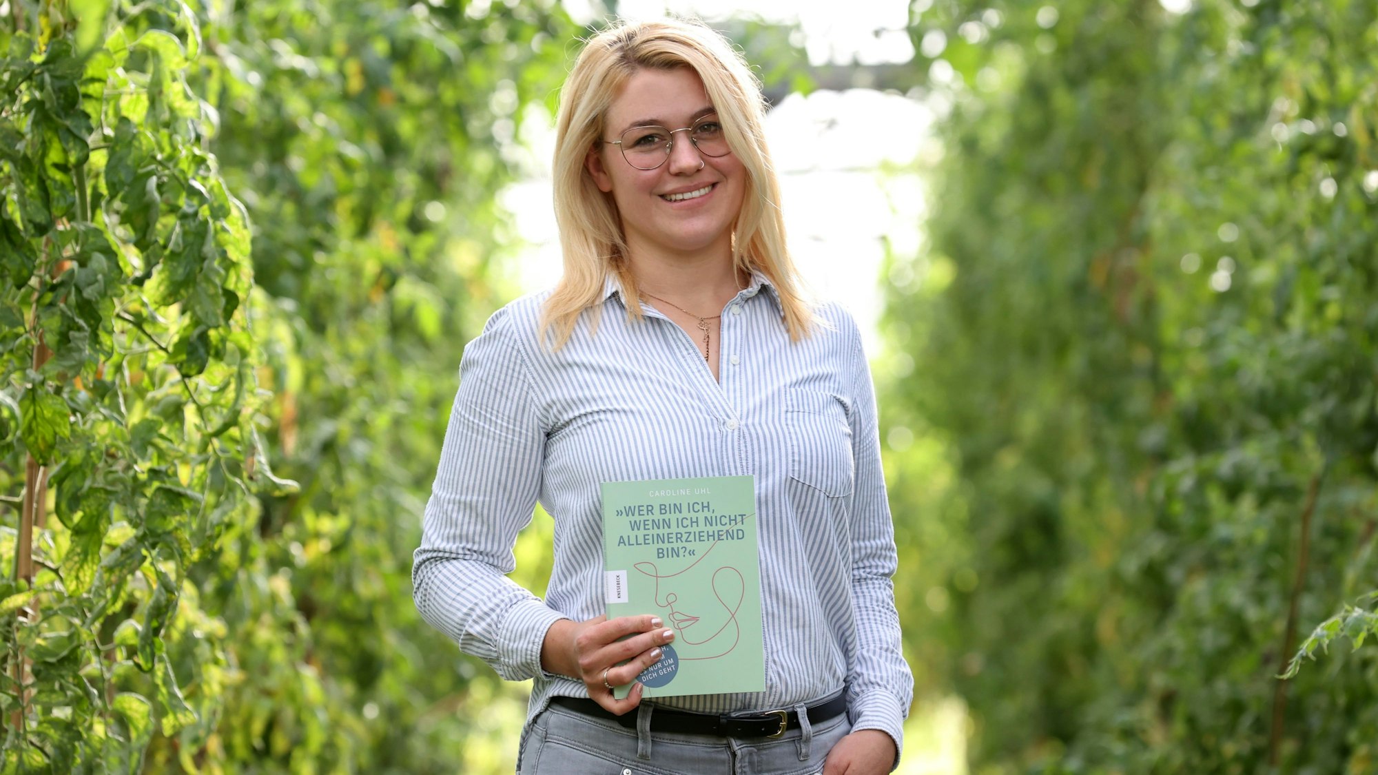 Caroline Uhl hält ihr Buch „Wer bin ich, wenn ich nicht alleinerziehend bin“ in die Kamera.