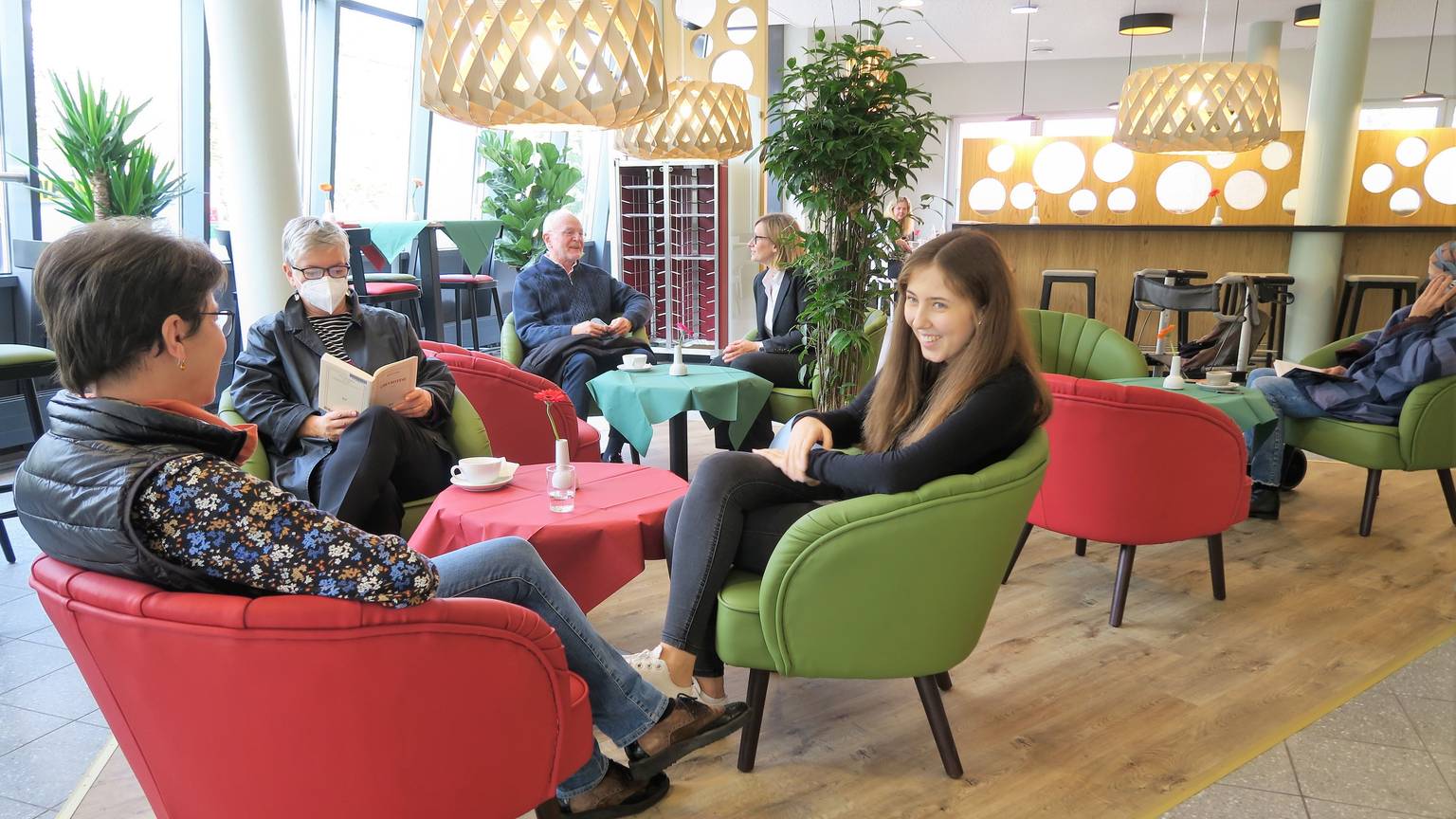 Im Inneren des „Culina“ in Köln-Kalk herrscht ein stylisches 50er Jahre-Flair. Sechs Personen sitzen in roten und grünen Sesseln an roten und grünen Tischen.
