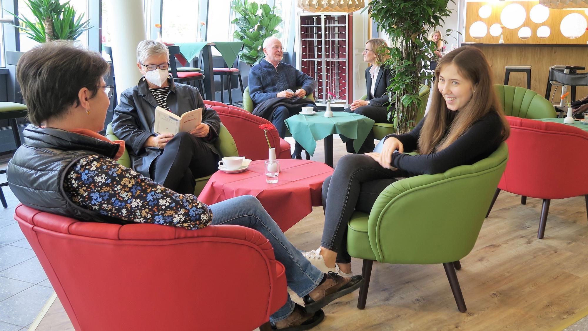Im Inneren des „Culina“ in Köln-Kalk herrscht ein stylisches 50er Jahre-Flair. Sechs Personen sitzen in roten und grünen Sesseln an roten und grünen Tischen.