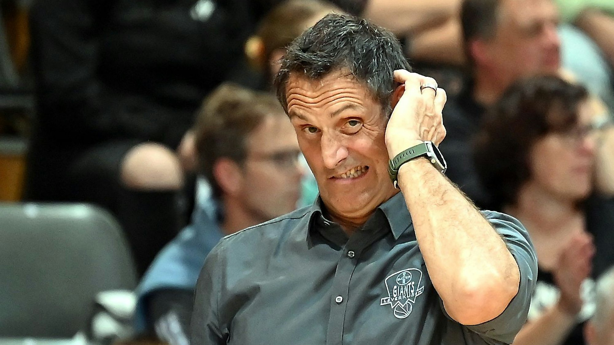 Ein Basketballtrainer steht am Spielfeldrand und kratzt sich nachdenklich am Kopf.