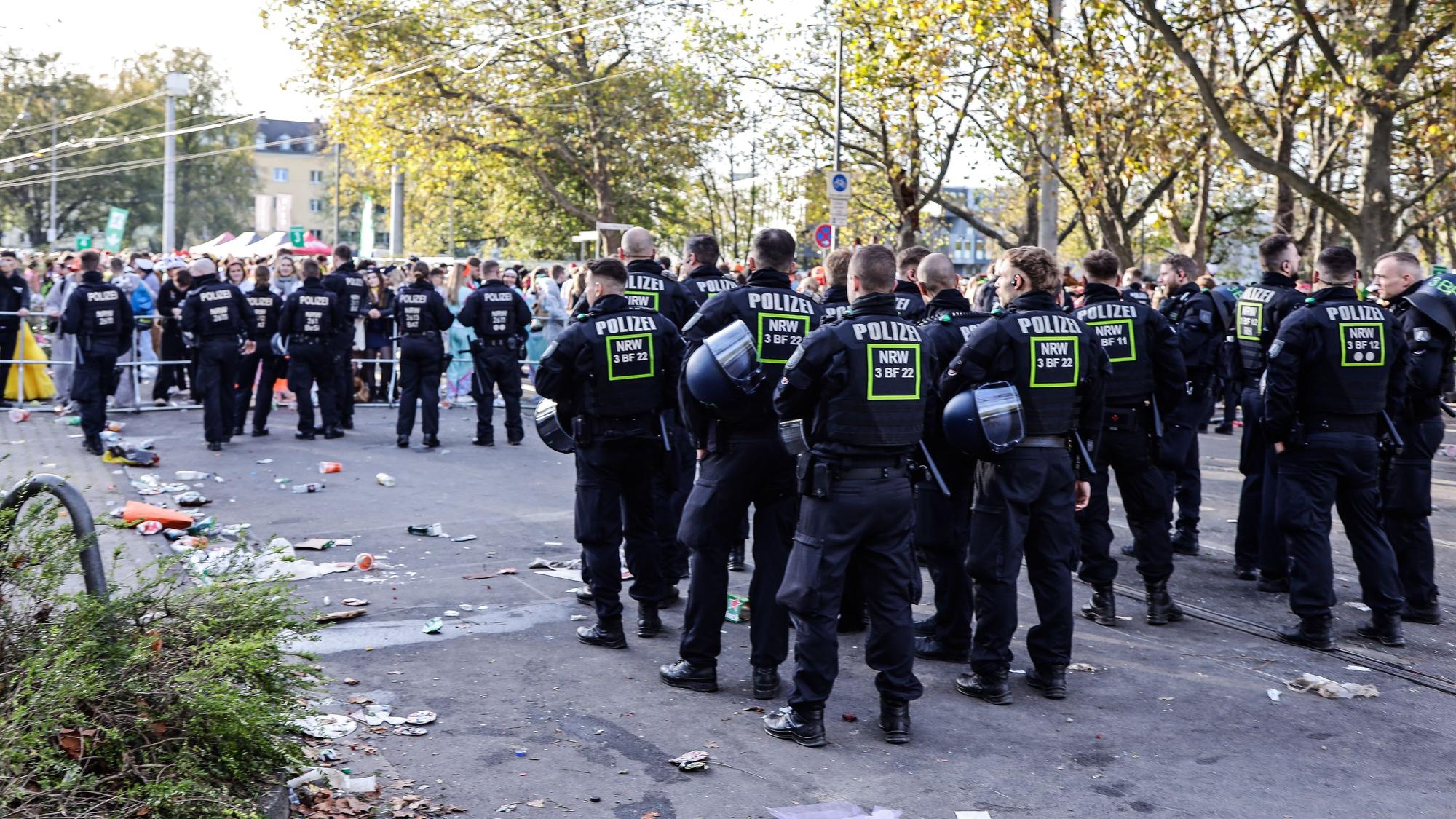 Polizisten einer Hundertschaft stehen in zwei Reihen hintereinander auf der Zülpicher Straße und sichern die Absperrgitter.