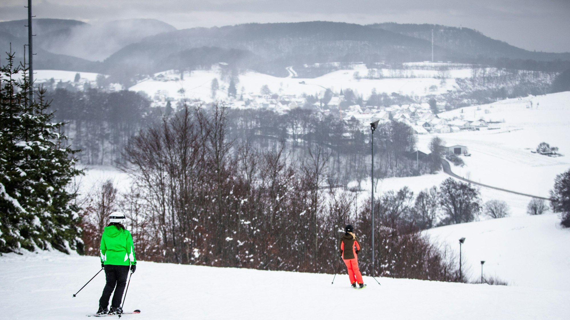 Auf einer Skipiste fahren zwei Skifahrer.