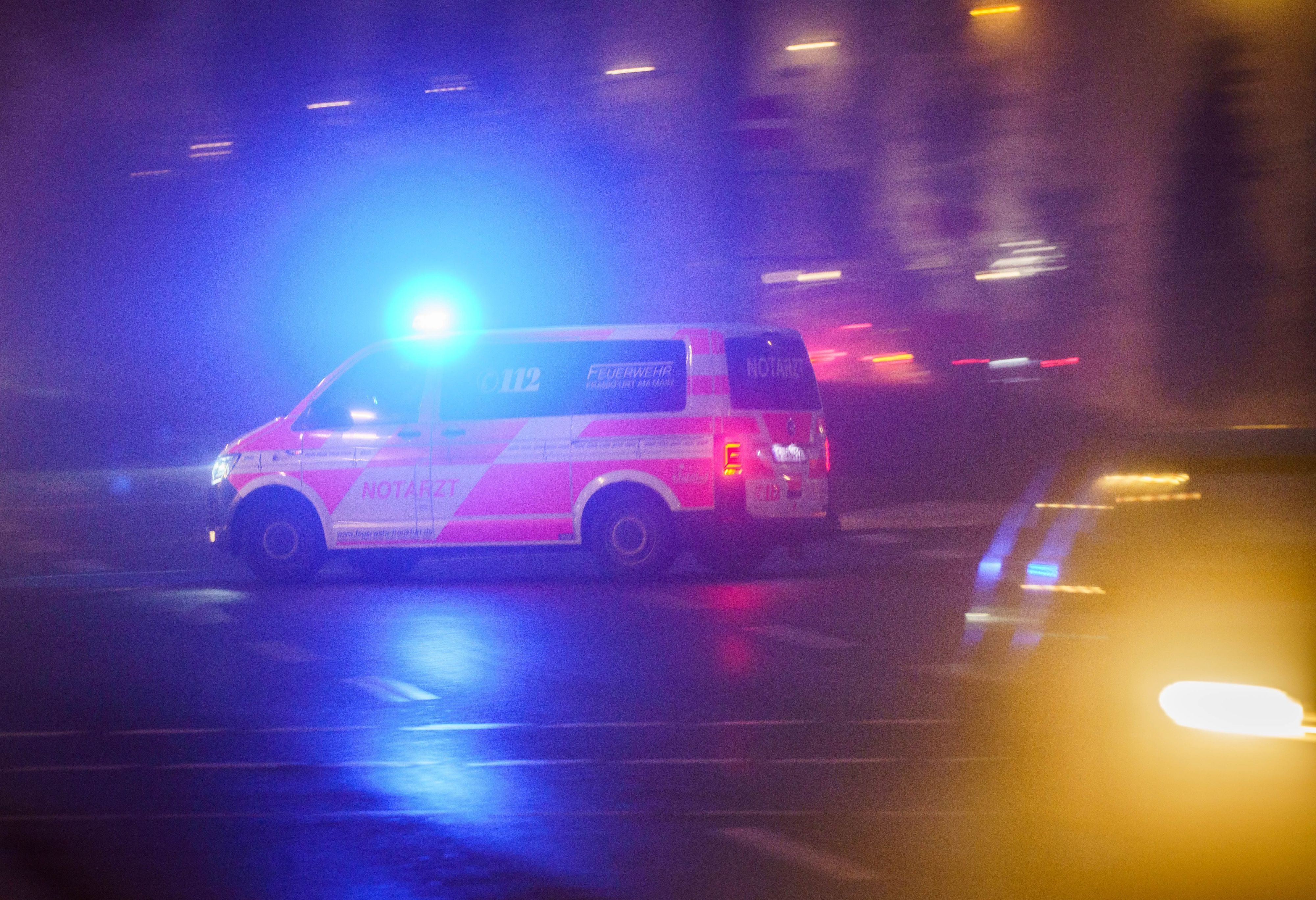 Ein Rettungsfahrzeug fährt mit Blaulicht über eine Straße, dabei ist es noch dunkel.
