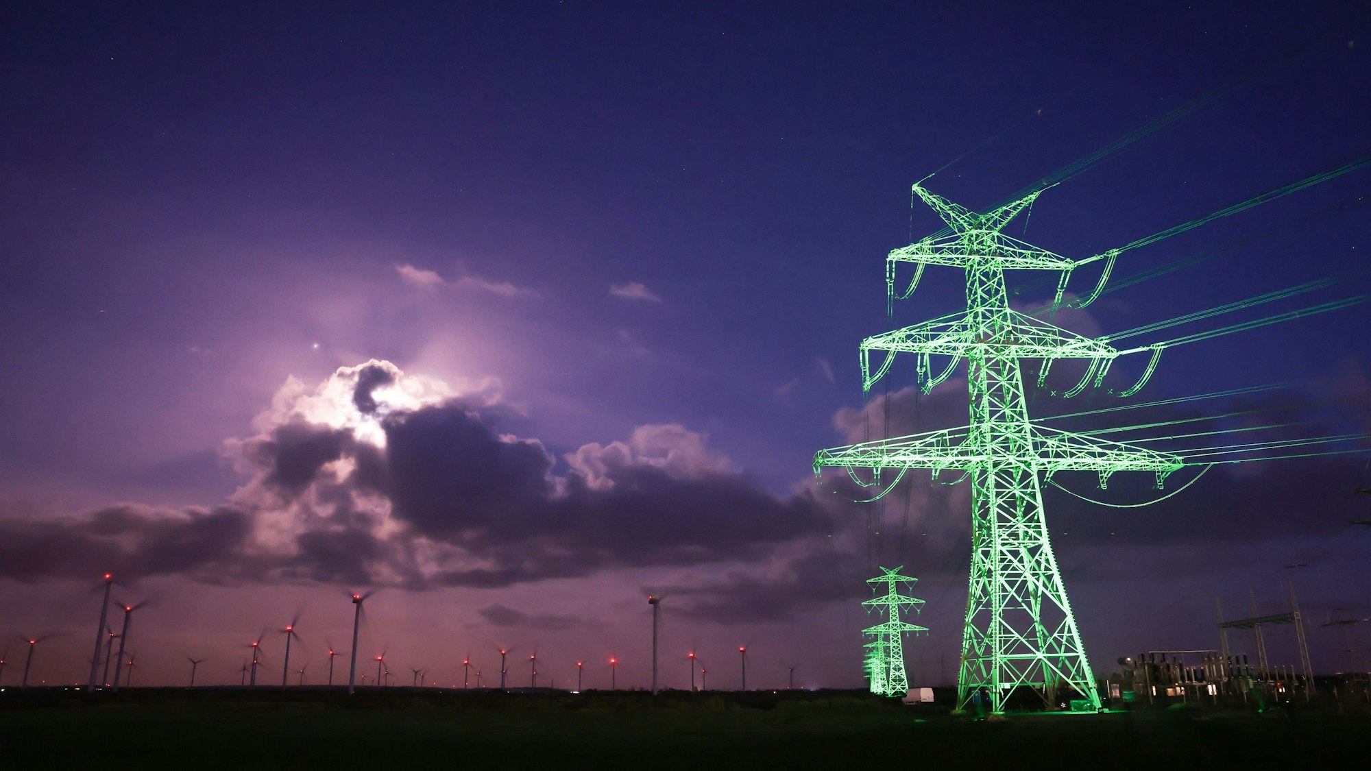 Strommasten einer Überlandleitung im nächtlichen Licht.