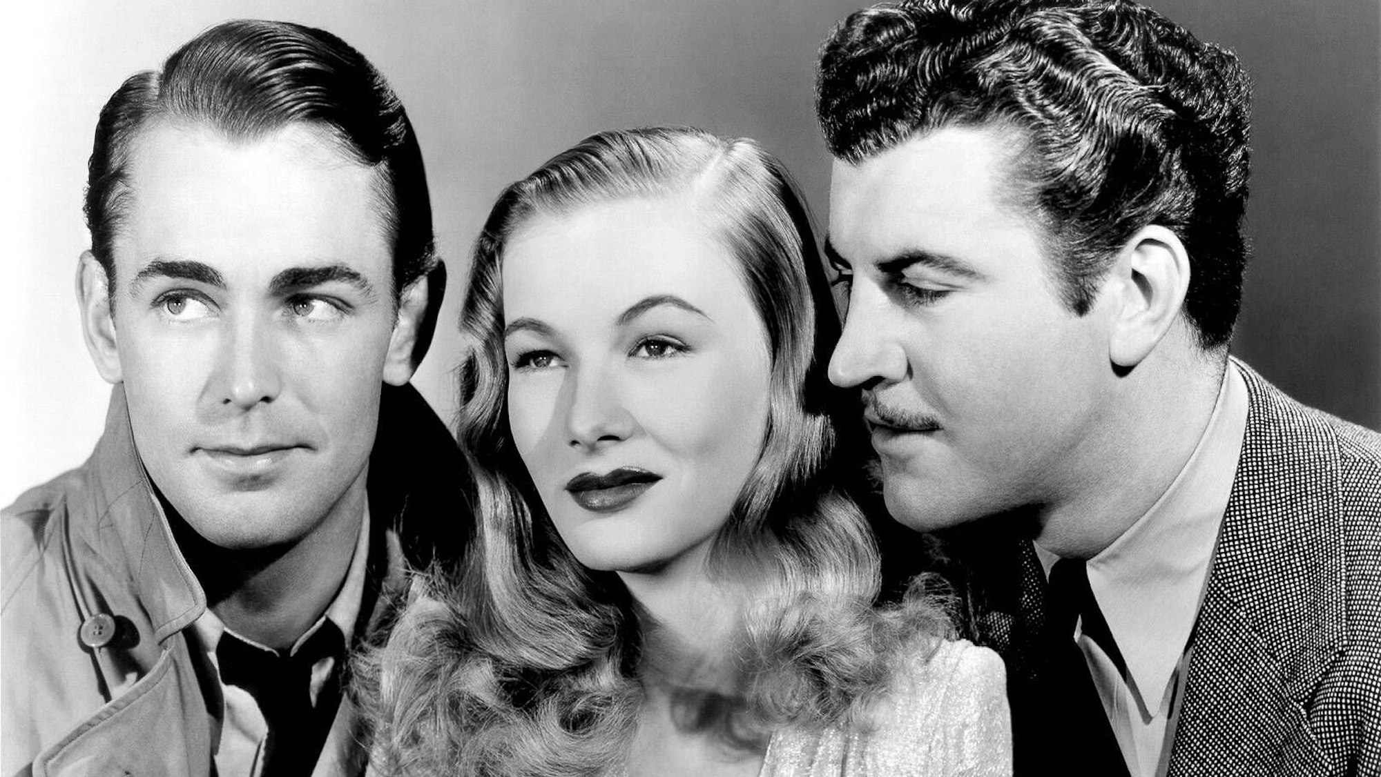 Nahaufnahmen von Alan Ladd, Veronica Lake und Robert Preston, die alle dezent lächeln.