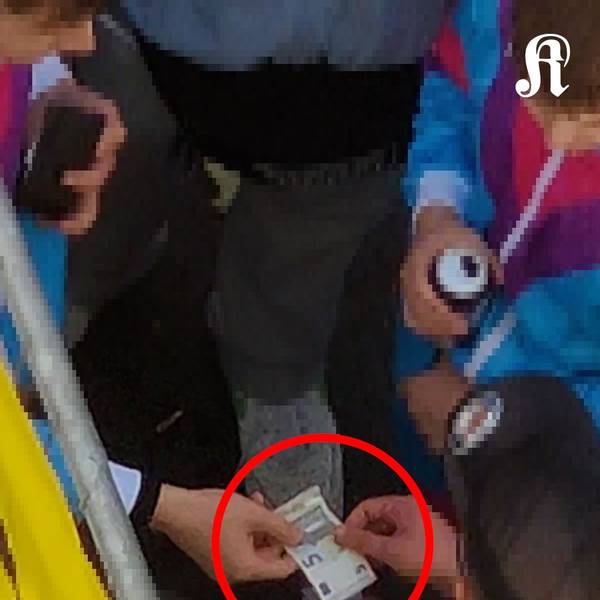 Ein kostümierter Mann drückt einem Ordner gut erkennbar 5 Euro in die Hand.