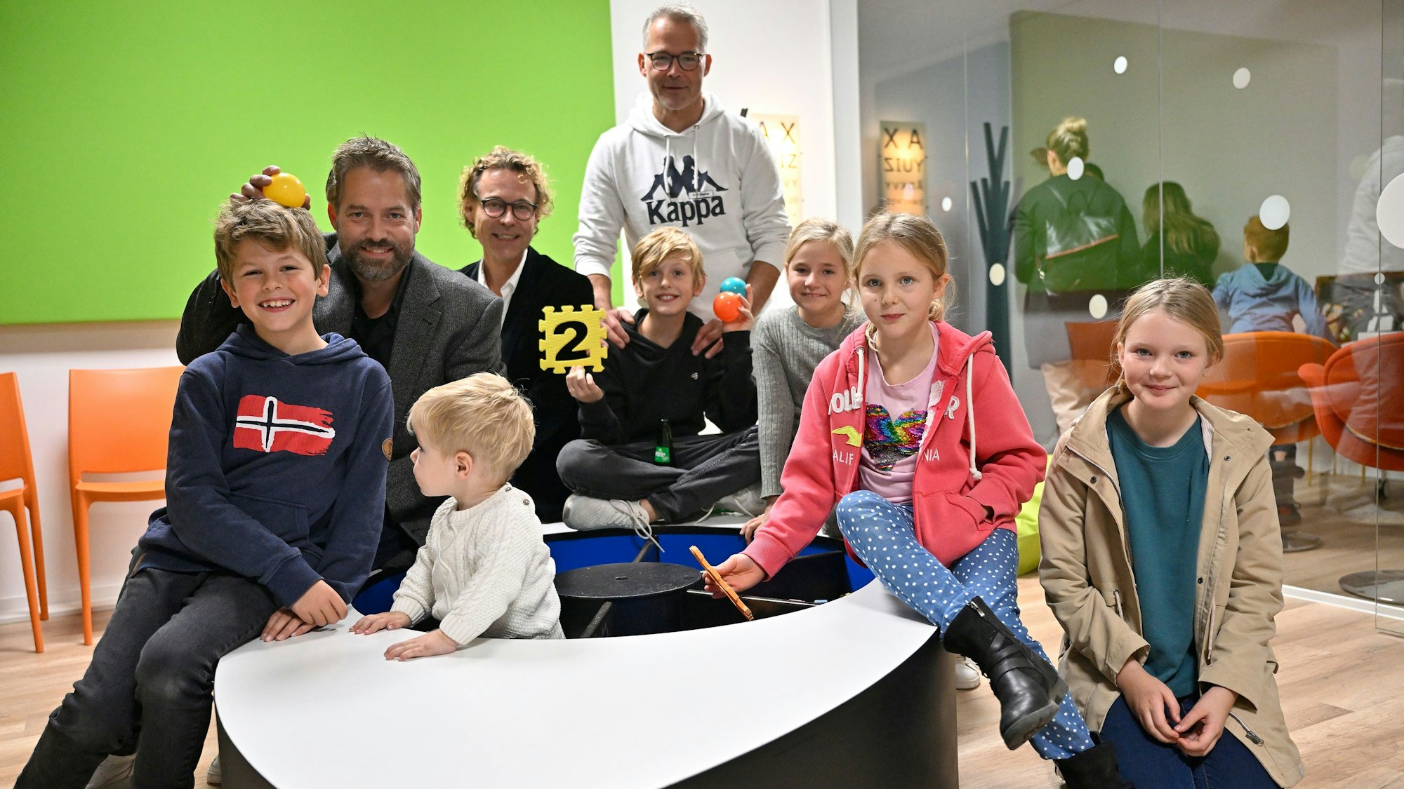 Andreas Stephan, Markus Stephan und Hans-Christian Brüggemann (v.l.) sitzen mit mehreren Kindern auf einer Sitzfläche.