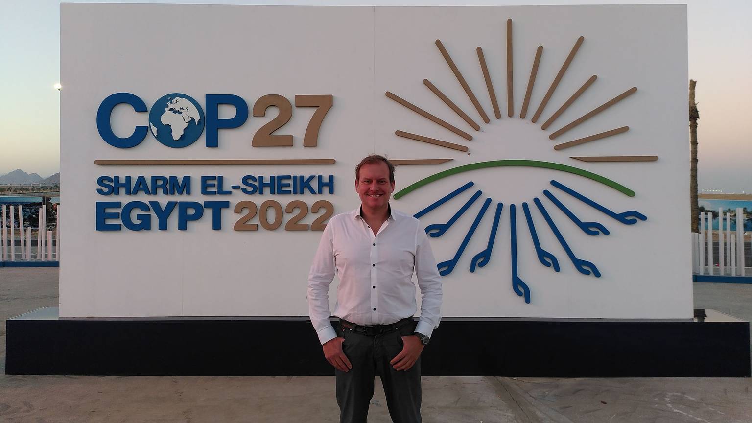 Sven Harten aus Drinhausen steht vor dem Schild der COP27 in Ägypten.