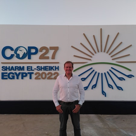 Sven Harten aus Drinhausen steht vor dem Schild der COP27 in Ägypten.