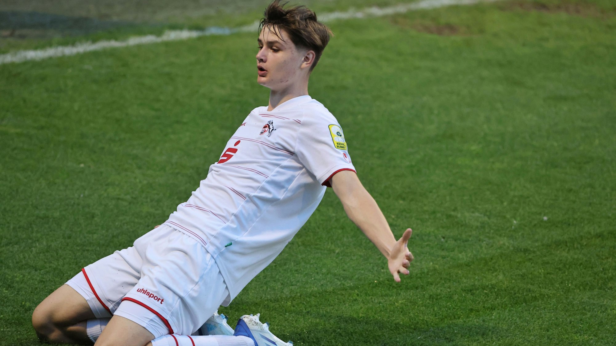Ein Fußballspieler rutscht auf Knien über den Rasen und feiert sein Tor.