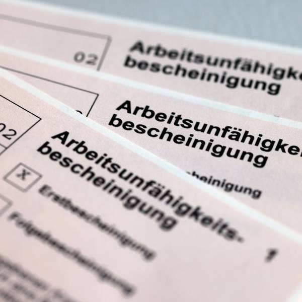 Drei Arbeitsunfähigkeitsbescheinigungen für Arbeitnehmer liegen aufgefächert übereinander.