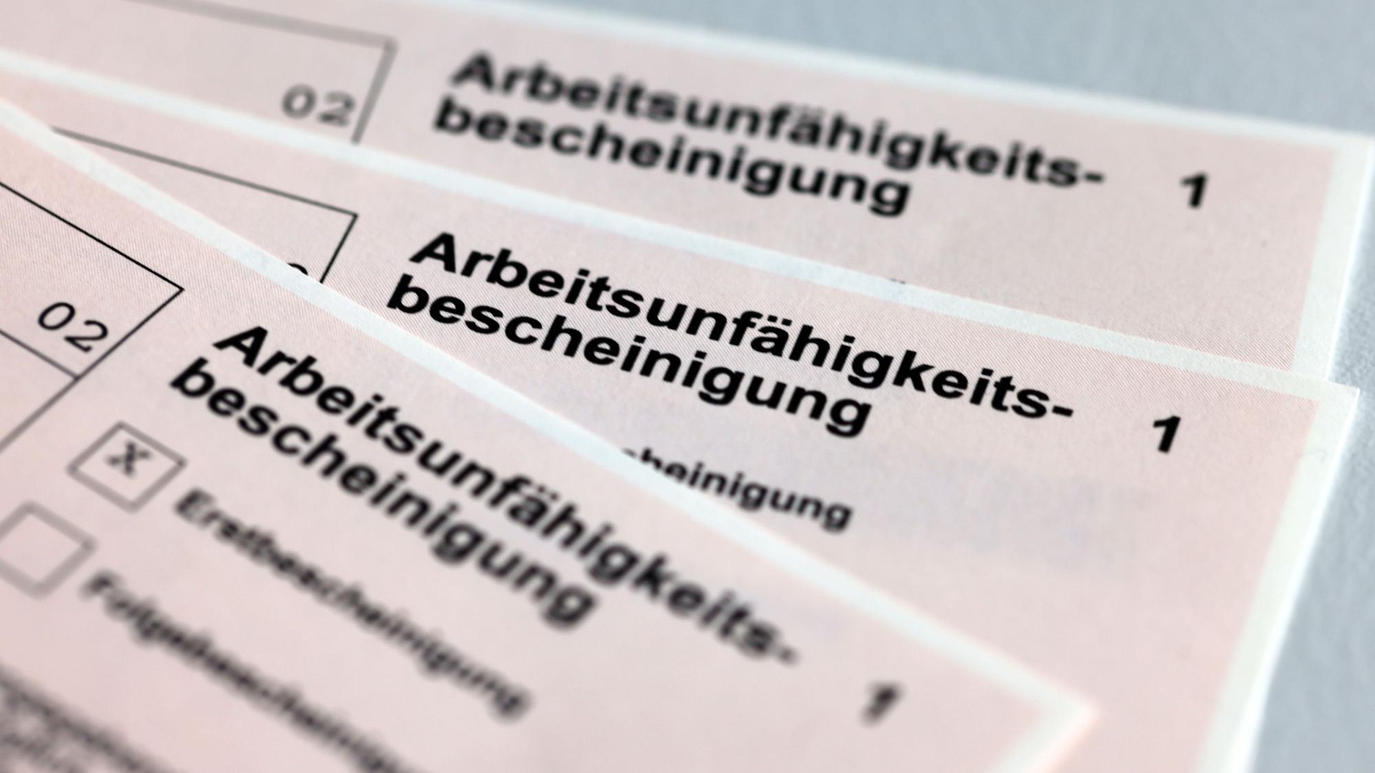Drei Arbeitsunfähigkeitsbescheinigungen für Arbeitnehmer liegen aufgefächert übereinander.