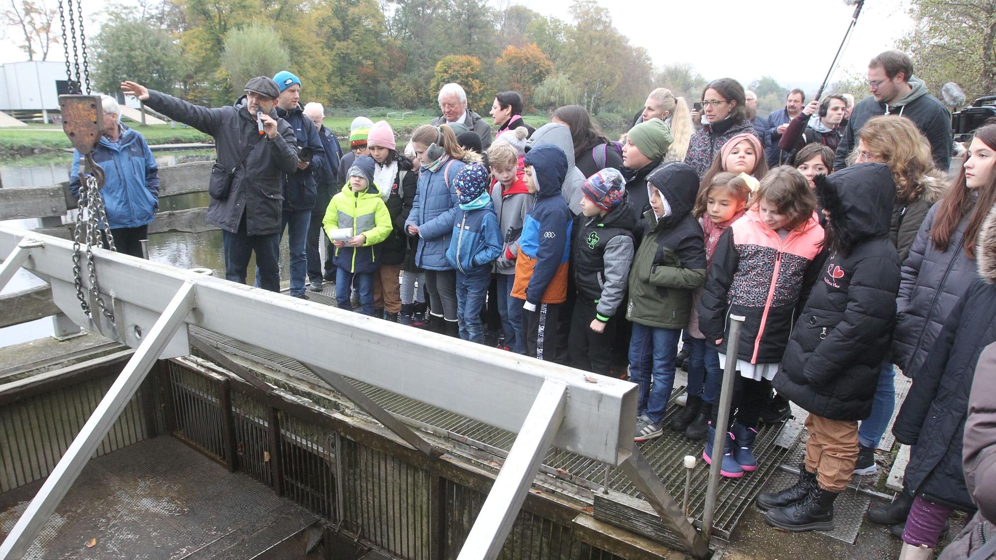 Schüler und NRW-Landwirtschaftsministerin Silke Görißen stehen am Siegwehr in Sankt Augustin-Buisdorf.