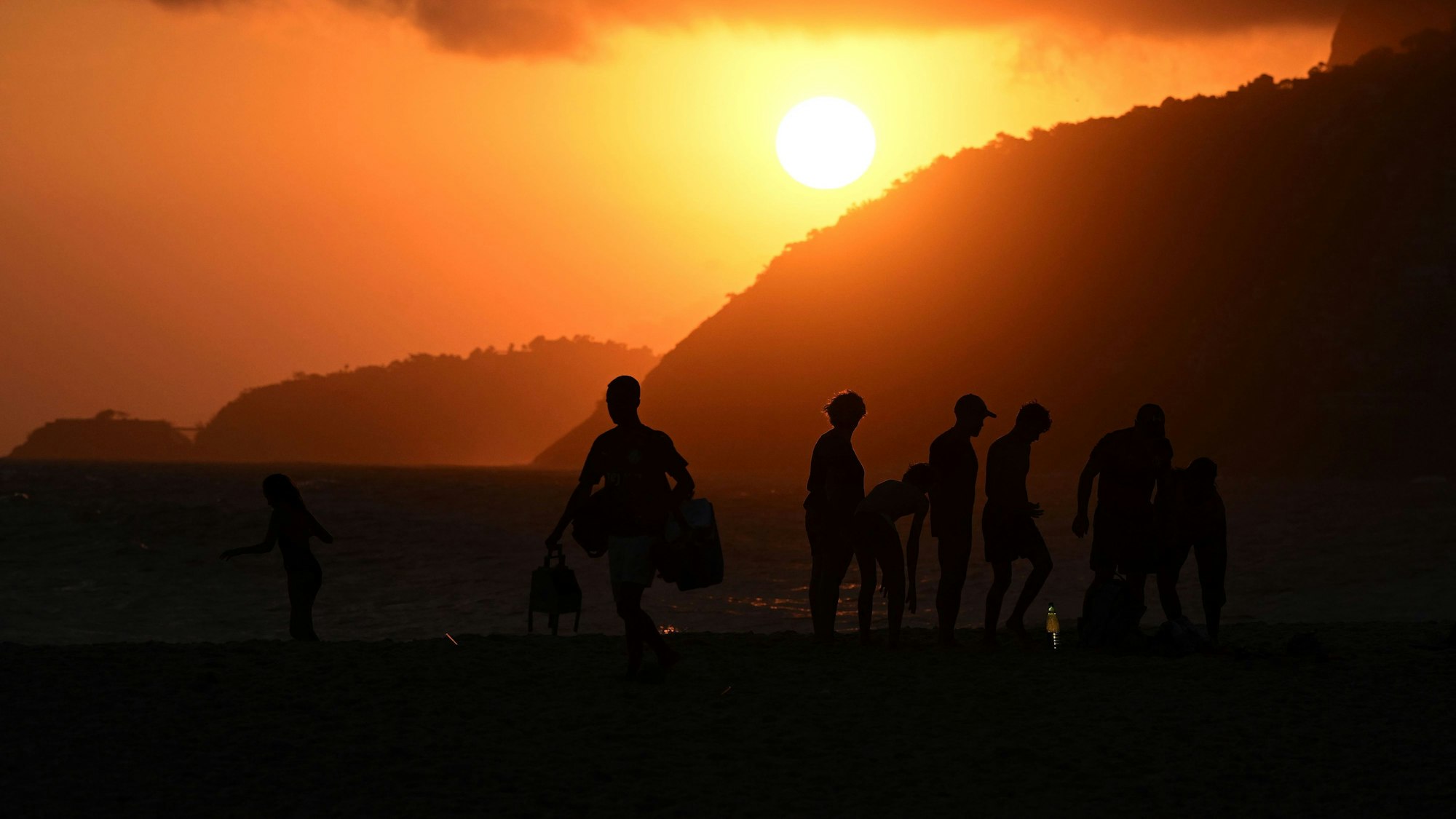 Menschen versammeln sich am Strand in Ipanema, um den Sonnenuntergang zu betrachten.