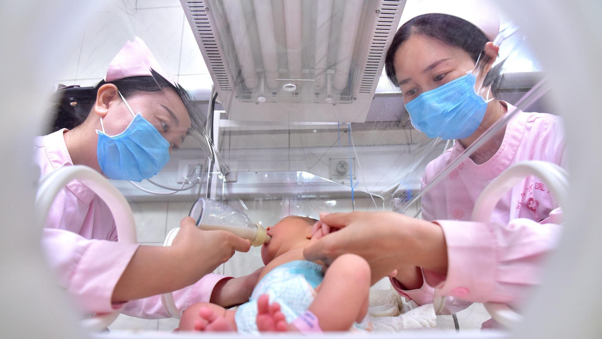 China, Shijiazhuang: Die Krankenschwestern Mo Fei (l) und An Keran geben in einem Krankenhaus in Xinle einem Neugeborenen ein Fläschchen.