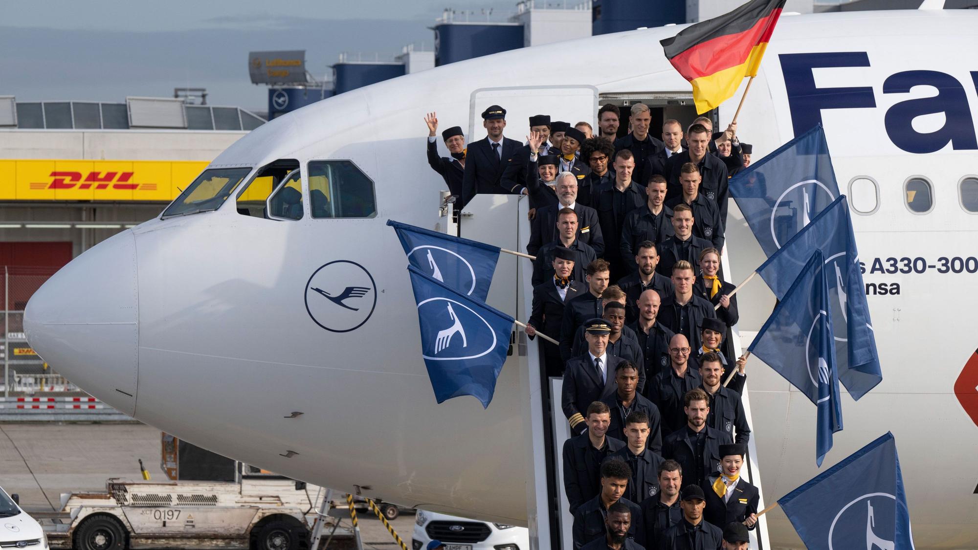 Trainer, Offizielle, Betreuer und Spieler der deutschen Fußball-Nationalmannschaft sowie Personal der Lufthansa stehen vor dem Abflug für ein Gruppenfoto auf der Gangway des Flugzeugs.