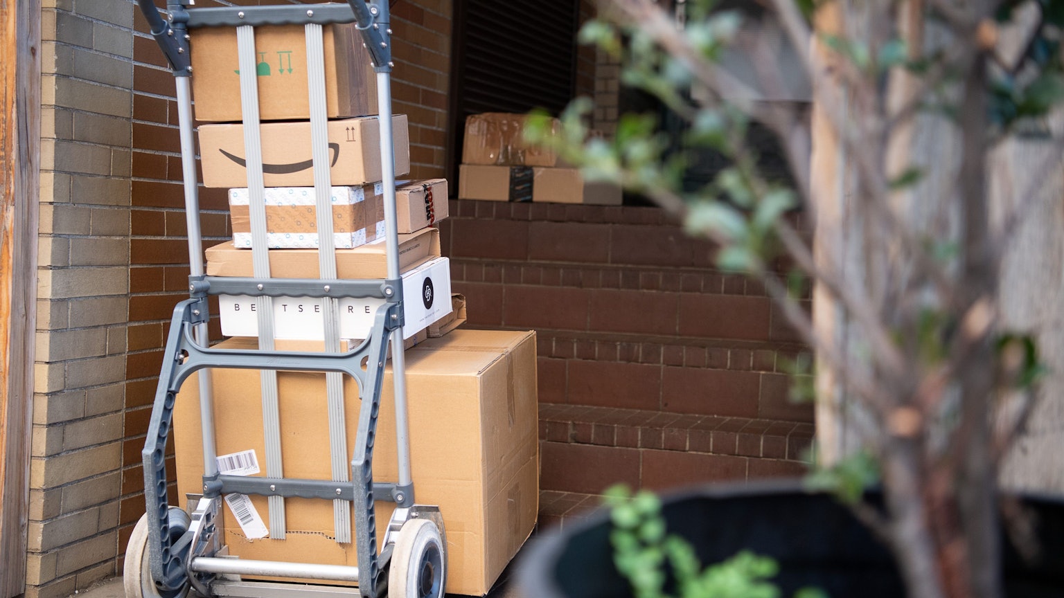 Eine Sackkarre mit mehreren Paketen steht in einem Hauseingang.