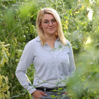Caroline Uhl steht inmitten grüner Pflanzen.