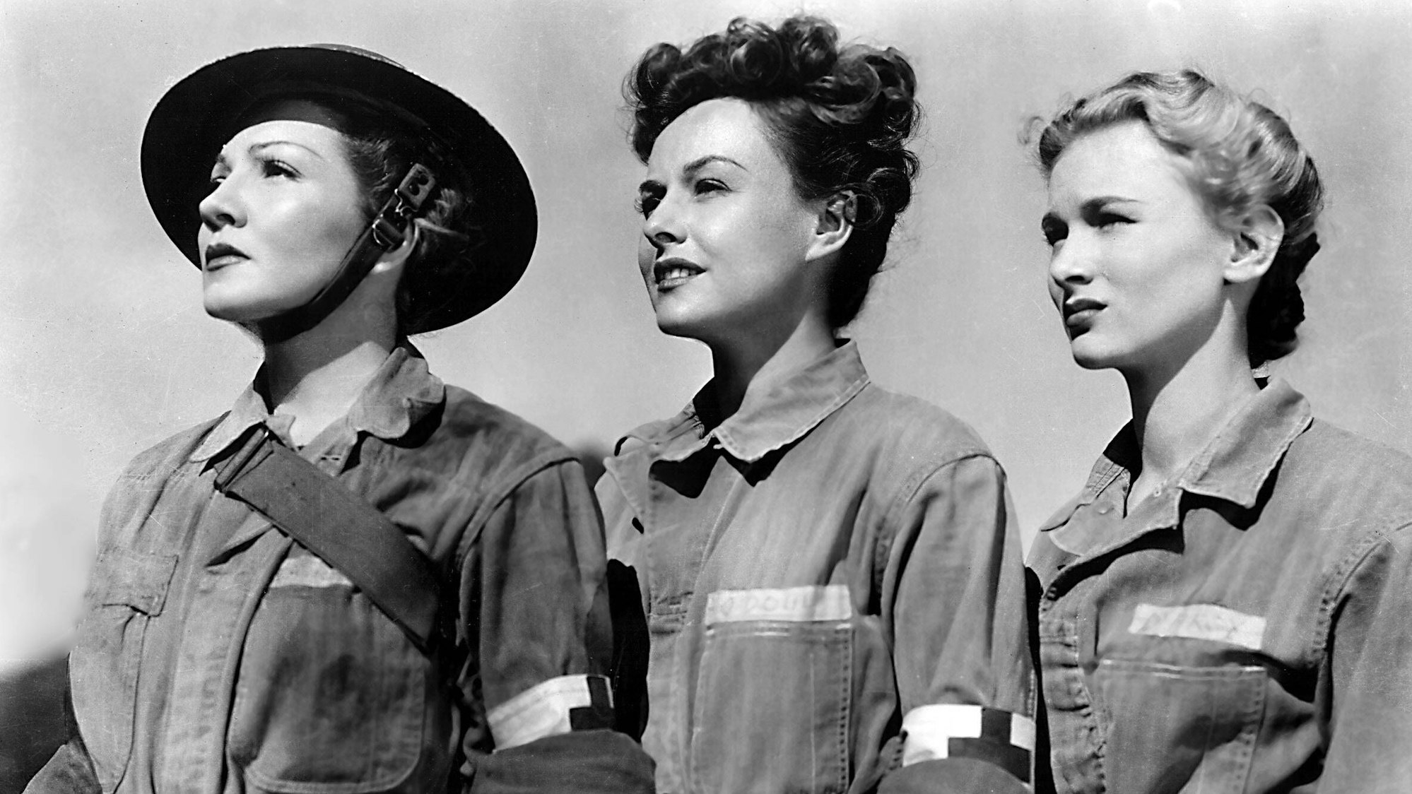 Claudette Colbert, Paulette Goddard, und Veronica Lake in Uniform. Sie schauen seitlich zum Horizont.