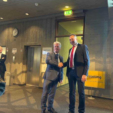 Olaf Krah (links) schüttelt seinem Kontrahenten Ralph Manzke die Hand. im Hintergrund ist ein Schild mit der Aufschrift „Wesseling“ zu sehen.