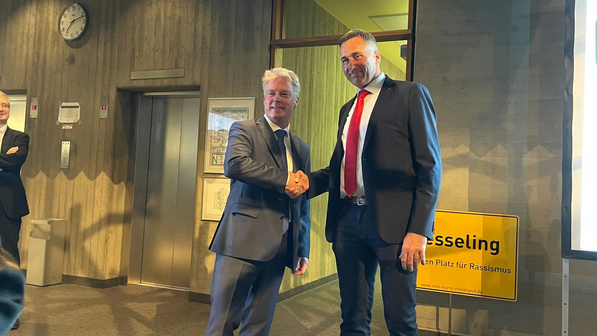 Olaf Krah (links) schüttelt seinem Kontrahenten Ralph Manzke die Hand. im Hintergrund ist ein Schild mit der Aufschrift „Wesseling“ zu sehen.