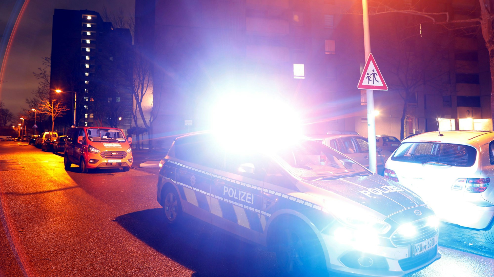 Ein Polizeiwagen steht vor einem Hochhaus im Kölner Stadtteil Chorweiler.