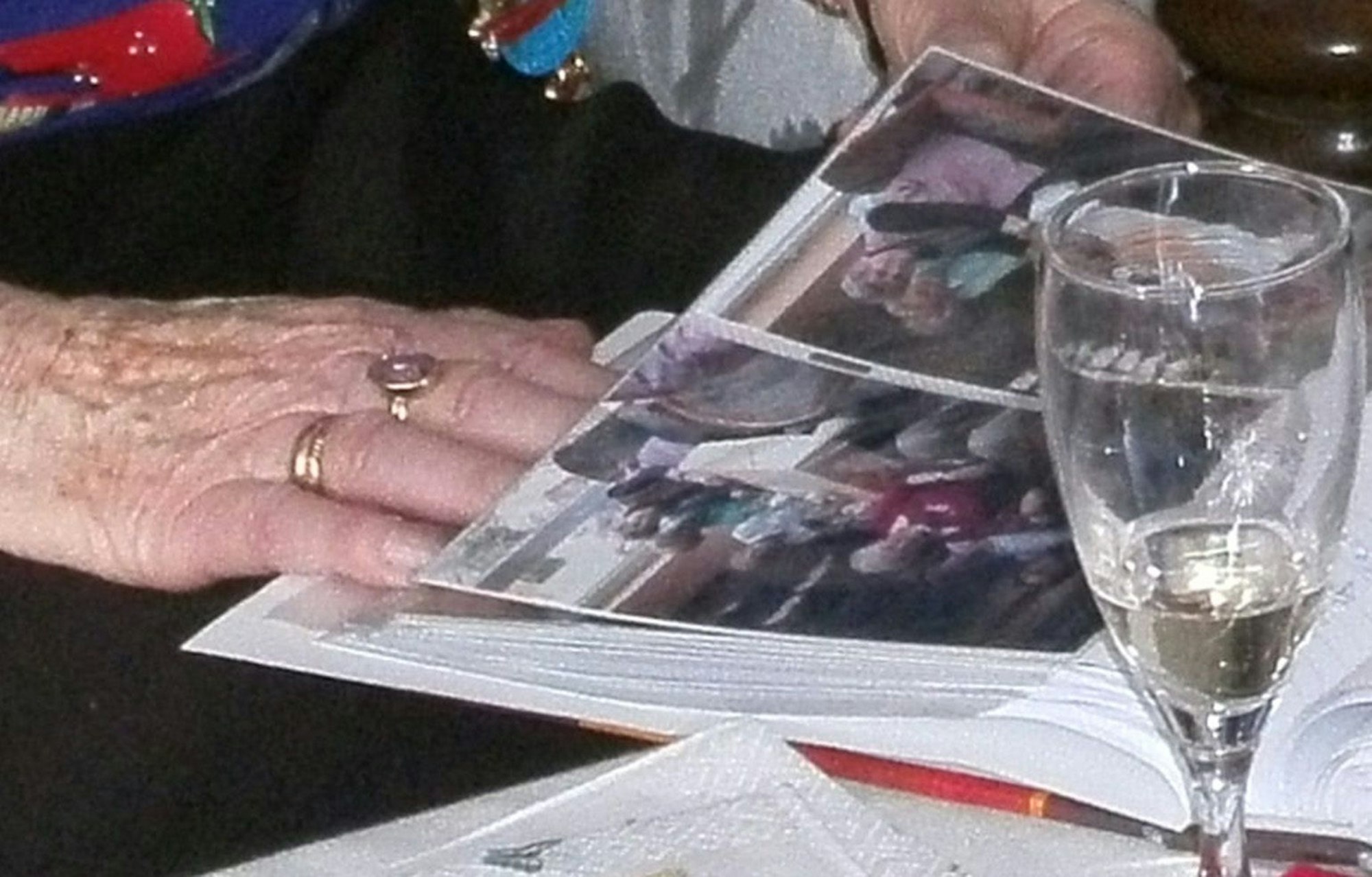 Frau Fülles Hand mit goldenen Ringen, ein Sektglas.