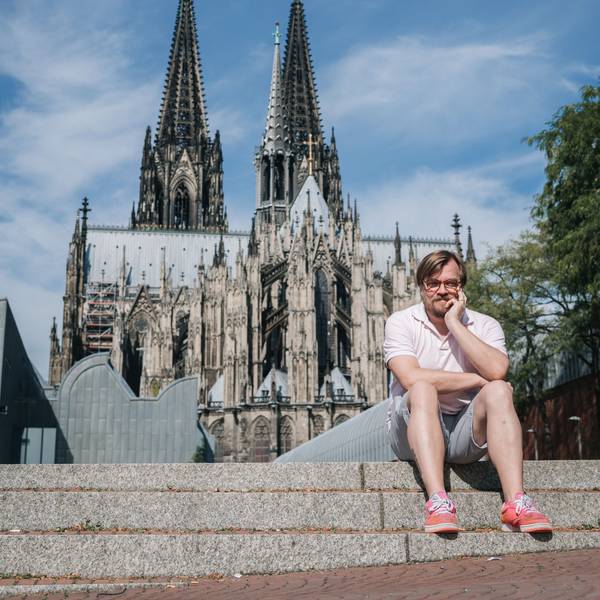 Der Moderator und Autor Nilz Bokelberg sitzt vor dem Kölner Dom.